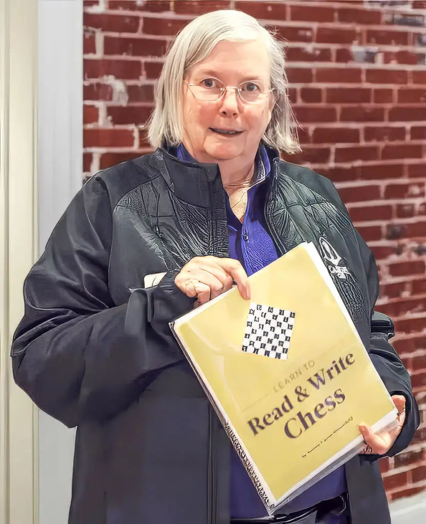 Dr. Jeanne Cairns Sinquefield holding the Learn to Read and Write Chess workbook