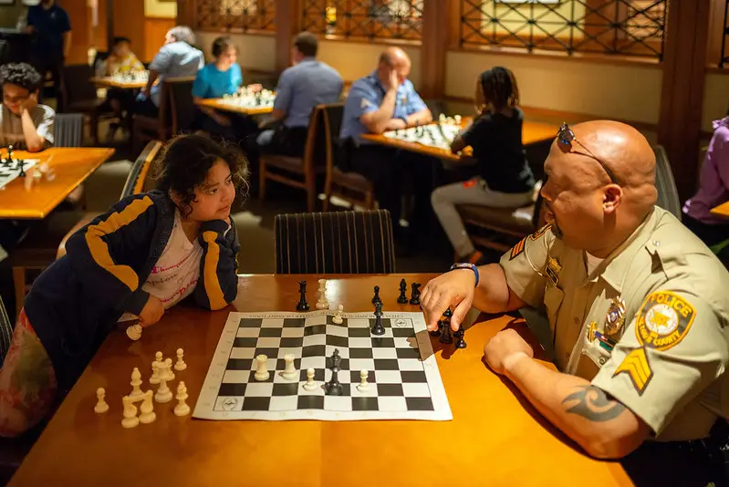 A police officer and a young girl playing chess